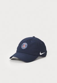 Jūros mėlynos spalvos audinio kepurė, papuošta apvaliu Paryžiaus Saint-Germain logotipu su raudonais ir baltais akcentais, bei ryškiu baltu Nike logotipu.