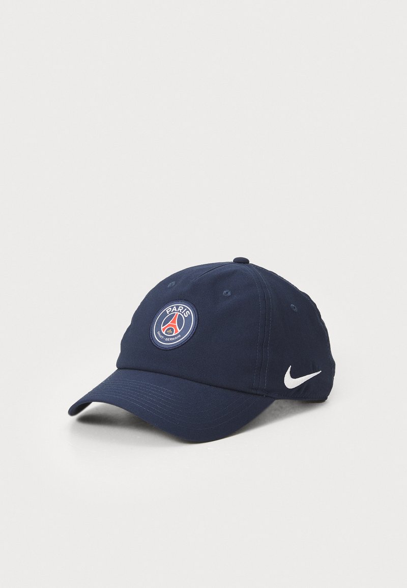 Jūros mėlynos spalvos audinio kepurė, papuošta apvaliu Paryžiaus Saint-Germain logotipu su raudonais ir baltais akcentais, bei ryškiu baltu Nike logotipu.