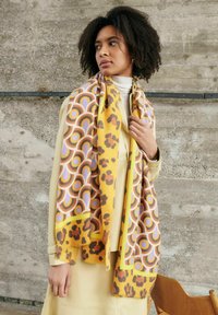 Gelber, gemusterter Schal mit kreisförmigen Designs in Braun, Lila und Akzenten im Leopardenmuster. Weicher Textil und fransige Ränder.