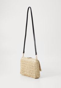 Vævet strå crossbody taske med rektangulær form, sort læderrem og hardware i guldfarve. Tekstureret overflade og klaplukning.