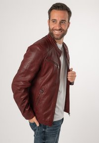 Bordeauxrote Lederjacke mit einem schlanken Design, ausgestattet mit einem Reißverschluss vorne und zwei seitlichen Taschen. Glatte Textur und taillierte Passform.