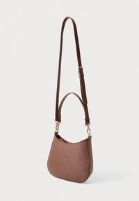 Bolsa de mão em couro castanho com uma forma curva. Apresenta uma alça longa e ajustável e acessórios em tom dourado. Textura suave, sem padrões visíveis.