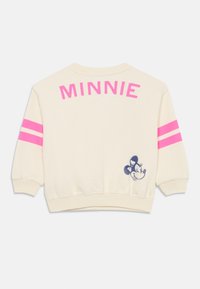 Kremfarget genser med rosa striper på ermene, "MINNIE" trykt på baksiden, samt en blå broderi detalj av Minnie Mus.