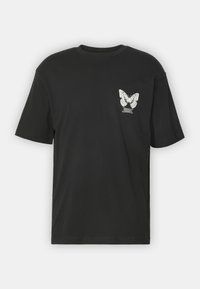 Black cotton t-shirt featuring a white butterfly graphic on the left chest area. Short sleeves and a crew neck design.