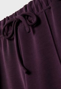 Lila Sweatpants mit glatter Textur, elastischem Bund mit gerafftem Detail und einer Kordel zum Verstellen.