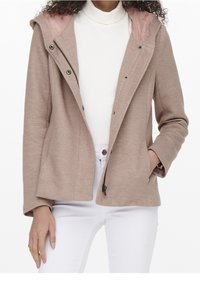 Světlounce hnědá texturovaná bunda s kapucí a růžovou vnitřní podšívkou. Má přední knoflíky, zipové zapínání a dvě boční kapsy.