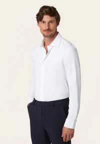 Witte blouse met lange mouwen en een button-down kraag, gemaakt van gladde stof. Combinatie met donkerblauwe broek met een stijlvol ontwerp.