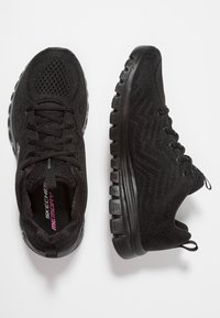 Svarta sportskor med mesh-tyg, rund tå, snörningsdesign och texturerad gummisula. Har "Memory"-logotyp på innersulan.