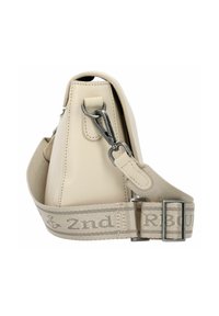 Borsa in pelle beige vista laterale che mostra la tracolla in tessuto beige regolabile con gancio metallico e dettagli ricamati di un'ancora e testo.