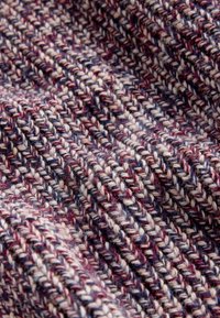 Pletená tkanina s textúrovaným vzorom v krémových, vínových a modrých odtieňoch. Nite sú pevne tkanej s viditeľnými vláknami a rôznou hrúbkou.