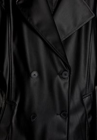 Manteau croisé en cuir noir avec un col large, deux gros boutons et des poches latérales, à la texture lisse.