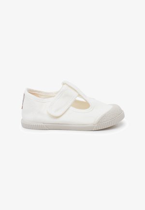 Scarpa Mary Jane bianca in tela con cinturino in velcro, punta arrotondata, suola in gomma e punta rinforzata testurizzata. Presenta un design perforato sul lato.