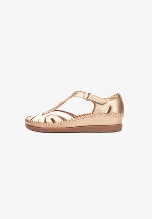Sandale compensée pour femme en cuir beige avec bride en T, semelle cousue, détails découpés, talon plat et fermeture à boucle réglable.