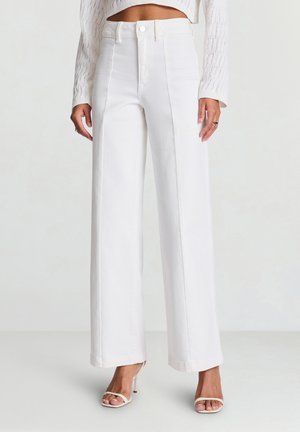 Pantalon blanc ample en coton, avec taille haute, plis sur le devant et fermeture par bouton. Texture lisse, longueur complète.