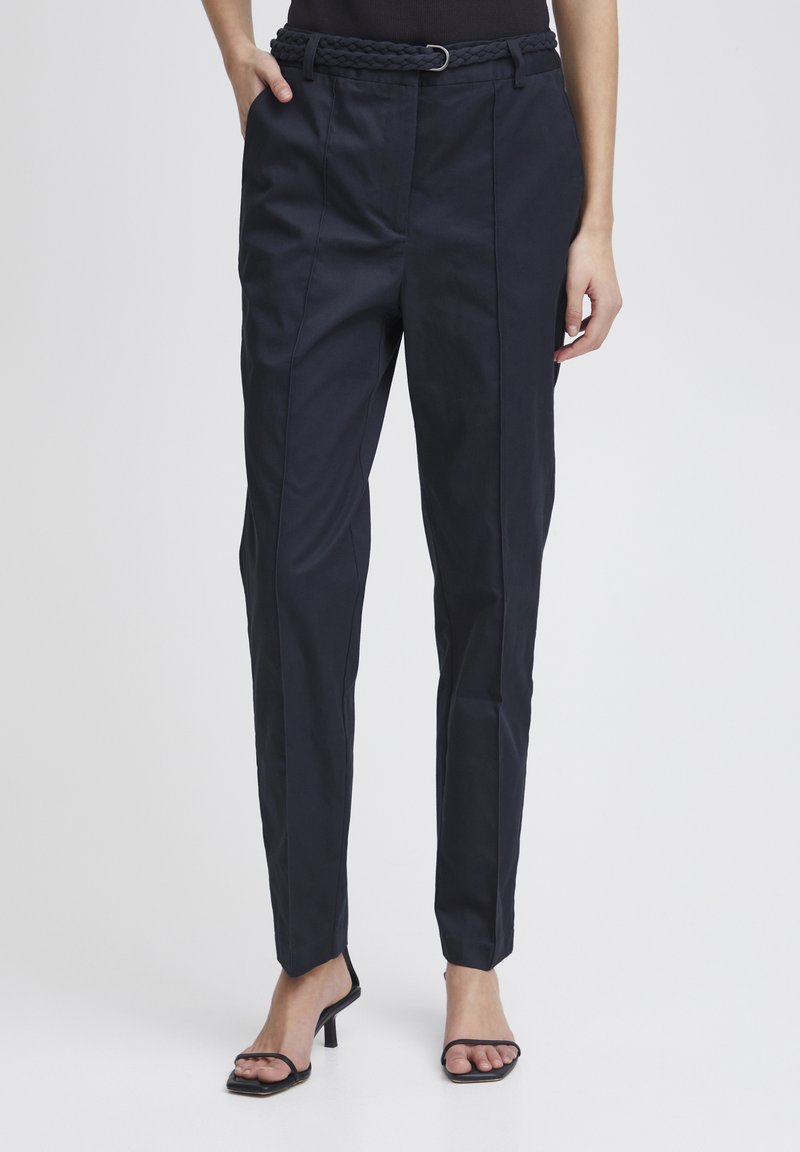 Pantaloni navy su misura con cintura intrecciata, design a gamba dritta, tasche frontali e superficie morbida. Finito con una silhouette elegante e minimalista.