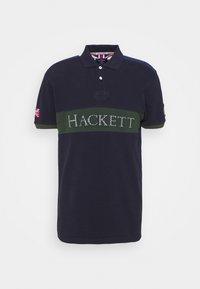 Marinblå polo med grön horisontell rand som har "HACKett" i kontrasterande bokstäver. Inkluderar krage och brittisk flagga på ärmen.