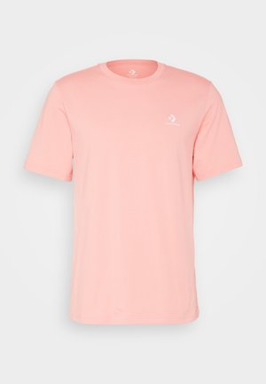 T-shirt rose clair à manches courtes et col rond avec un petit logo blanc Converse sur la poitrine gauche.