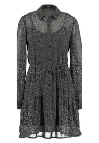 Vestito nero a pois con bottoni sul davanti, maniche lunghe e gonna a strati. Realizzato in tessuto trasparente, presenta un colletto.