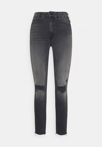 Vaqueros ajustados de tiro alto en negro con decoloración gris, parches desgastados en las rodillas, dobladillo deshilachado y diseño clásico de cinco bolsillos.