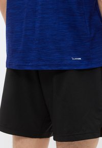 Modra športna majica z teksturiranim videzom in logotipom "CLIMACOOL", kombinirana s črnimi kratkimi hlačami z gladkim zaključkom in všitimi robovi.
