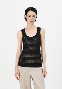 Svart strikket tanktop med ermeløs design, teksturerte striper og åpne strikkemønstre. En ribbestrikket kant fullfører utseendet.