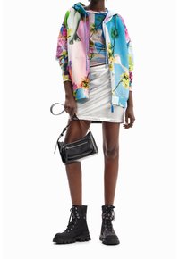 Färgglad hoodie med blommönster, åtsittande crop top, metallic silverkjol, svart handväska och ankelstövlar med snörning och tjock sula.