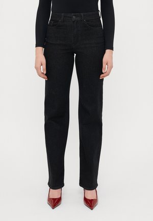 Jeans negre din denim, cu croială dreaptă, cinci buzunare, cusături subtile și talie medie, asortați cu pantofi cu toc din piele patentată roșie.