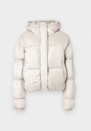 Šviesiai smėlio spalvos pūkinė striukė su gobtuvu, ilgomis su siūlais dygsniuotomis rankovėmis, priekyje užtrauktukas, dengtas plačiu atvartėliu, ir ribinėmis rankogaliais.