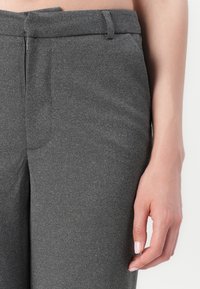 Grå skreddersydde bukser laget av strukturert materiale, med et elegant design, frontlomme og en linning med en diskret lukking.