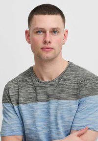 Pruhované tričko s horizontálním designem v černé, šedé a modré barvě. Krátké rukávy, kulatý výstřih a měkká textilie.