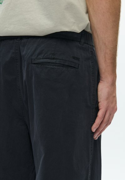 Μαύρο, ελαφρύ παντελόνι από ύφασμα με άνετη εφαρμογή, που διαθέτει πίσω τσέπη και διακριτικό λογότυπο. Λείο υλικό με ελάχιστες σχεδιαστικές λεπτομέρειες.