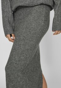 Falda de punto acanalado gris con una silueta ajustada y una abertura lateral. Textura suave, de longitud media, con una cintura ancha.