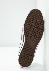 Braune Gummisohle mit diamantetzungsmuster, weißen Seiten und schwarzem Rand. Mit "Converse All Star" Branding auf der Sohle.