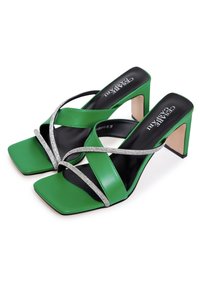 Sandale cu toc înalt din piele verde, cu vârf pătrat, curele încrucișate accentuate cu strasuri și un design cu toc bloc. Tălpică neagră.