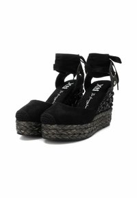 Zapatos de cuña de ante negro con suela de yute trenzado, que cuentan con una puntera texturizada, lazos de cinta en el tobillo y detalles decorativos en el lateral.