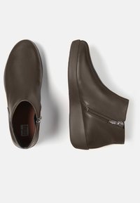 Stivaletti in pelle marrone con finitura liscia, dettaglio con zip laterale e suola in gomma spessa. Design elegante e minimalista con punta rotonda.