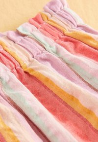 Multikleurige gestreepte stof met een gerimpelde textuur, met roze, oranje, lavendel en muntgroene strepen van verschillende breedtes. Zacht, lichtgewicht materiaal.