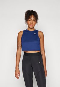 Marineblå cropped atletisk tanktop lavet af strækbart stof, med rund udskæring og tre hvide skrå striber på brystet.