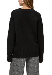 Schwarzer Pullover mit geripptem Saum und Bündchen, mit lockerer Passform und Raglanärmeln. Stricktextur, glatte Oberfläche, schlichtes Design.