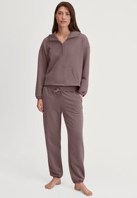 Helllilafarbener Pullover mit Reißverschlusskragen und Fronttasche, kombiniert mit passenden Jogginghosen mit elastischem Bund und Bündchen.