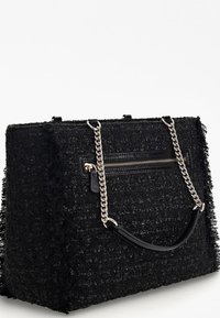 Černá texturovaná kabelka vyrobená z tkaného materiálu s roztřepenými okraji. Má stříbrný řetízkový popruh a na přední straně kapsu na zip.