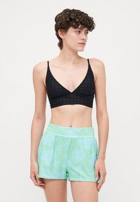 Black textured triangular bralette paired with light green shorts featuring a floral pattern, elastic waistband, and loose fit.