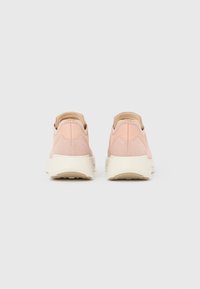 Ζευγάρι ανοιχτόροζ πάνινα παπούτσια slip-on με υφασμάτινη υφή και χοντρές εκρού σόλες, εμφανιζόμενα από πίσω πάνω σε απλό λευκό φόντο.