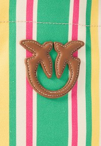 Gestreepte stof met groene, roze, gele en witte kleuren, met een bruine leren logo-detail in de vorm van twee bladeren.