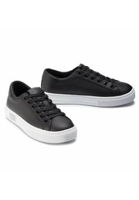 Black leather sneakers with a low-top design, round toe, white rubber sole, and black lace-ups. Features logo detail on the side.