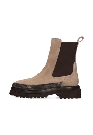 Beige Wildleder-Stiefelette mit dunkelbraunen elastischen Seiteneinsätzen, strukturierten metallischen Details um die Sohle und einer dicken schwarzen gummierten Profilsohle.