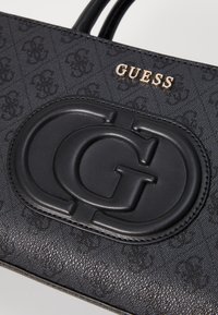 Borsa a tracolla in pelle nera con logo GG impresso e marchio "GUESS" in oro, con superficie testurizzata e doppi manici.
