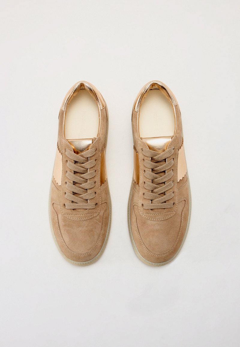Sneakers in suede tan con accenti metallici, punta arrotondata, sei fori per i lacci e un pannello laterale testurizzato. Suola in gomma con un leggero battistrada.