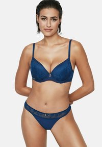 Marineblauwe kanten bh met een diep uitgesneden halslijn en padded cups, gecombineerd met bijpassende bikini-achtige slipjes met kantafwerking.
