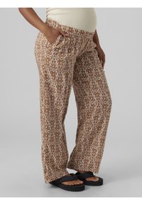 Brązowe spodnie ciążowe w wzory z elastycznym pasem, dwoma bocznymi kieszeniami i luźnym krojem. Tkanina ma białe abstrakcyjne wzory.